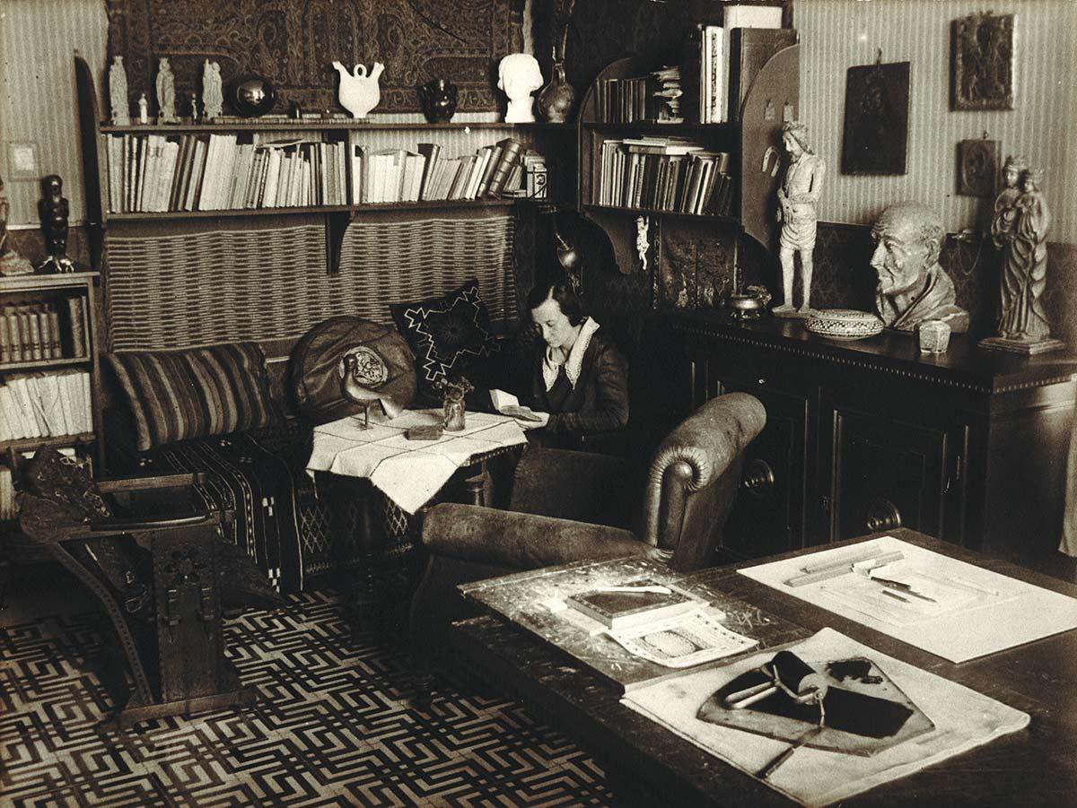 Jetta in de woonkamer van het huis aan de Via Alessandro Poerio in Rome, voorjaar 1931. Op de voorgrond liggen hulpmiddelen voor het drukproces, waaronder het lepeltje.